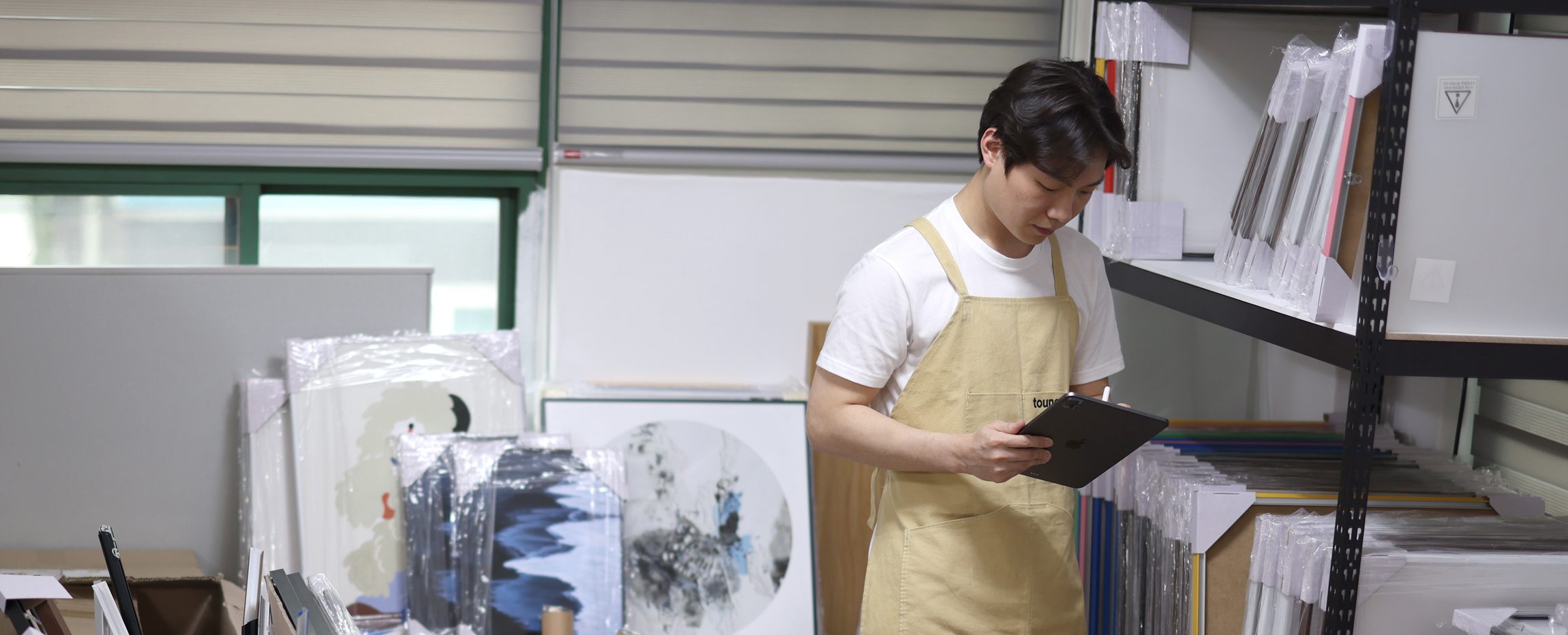 작업실에서 태블릿으로 작품을 확인하고 정리하는 장면